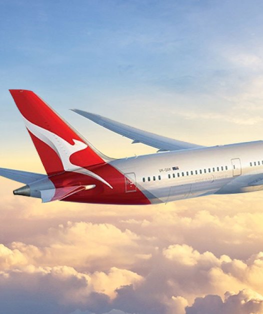A Qantas aircraft above the clouds at sunrise
